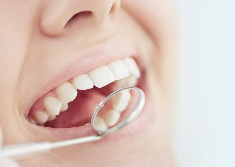 Close-up of a person smiling and looking into a mirror for dental check, showing white teeth.