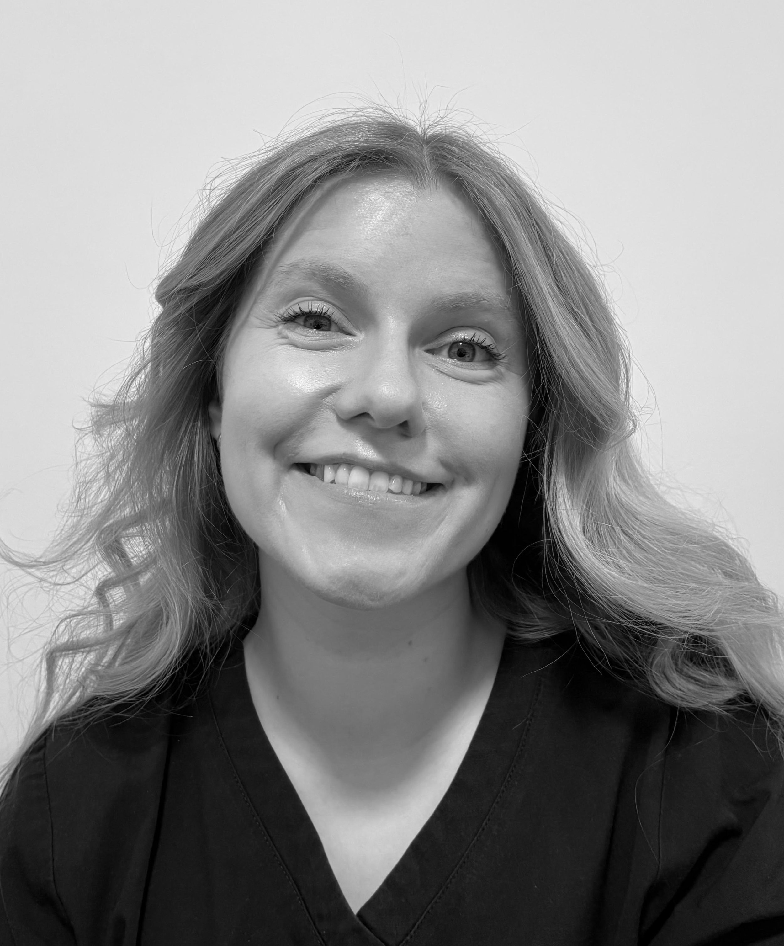 Black and white portrait of a smiling woman with wavy hair.