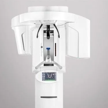 A large white medical imaging machine, likely a CT or MRI scanner, with a control screen and an opening for a patient to lie inside.