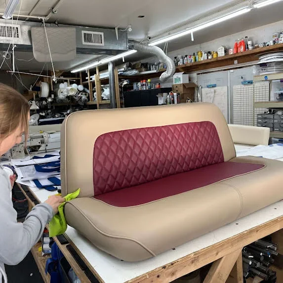 Sherpa-style upholstered bench with beige exterior, red diamond-quilted interior, and red backrest cushion, placed on a worktable at Robie Canvas just before installation