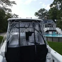 A boat docked near a lake with a house and trees in the background.