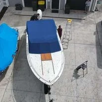 Boat on display in an indoor store, with a blue cover and a shopping cart nearby.