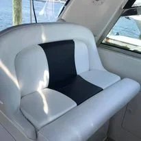 White Searay boat seat custom fabricated by Robie Canvas with a navy blue and white cushion, near a window overlooking water and boats