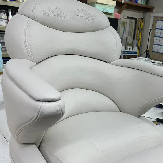 White vinyl Sea Ray boat captain's chair with armrests in the Robie Canvas workshop, completely redone.