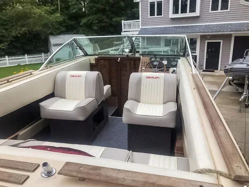 Interior view of a vintage boat with two front seats and a steering wheel, with all seats recovered professionally by Robie Canvas.