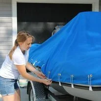 A Robie Canvas employee performing the final touches on a custom mooring cover install on a 17 foot Zodiac RIB. 
