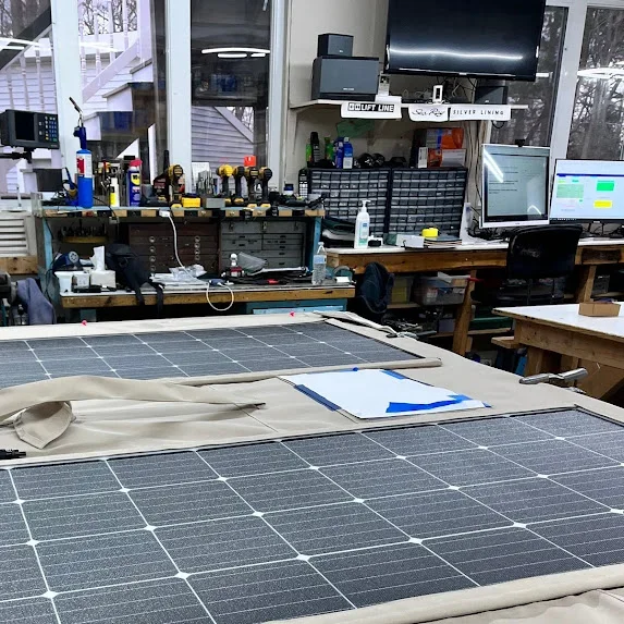 Workbench with solar panels and tools in a workshop with computer monitors and storage bins