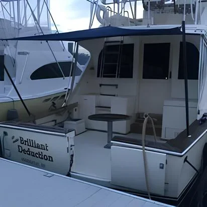 Back view of a white boat docked at a marina, with seating area and steps leading to a higher deck.