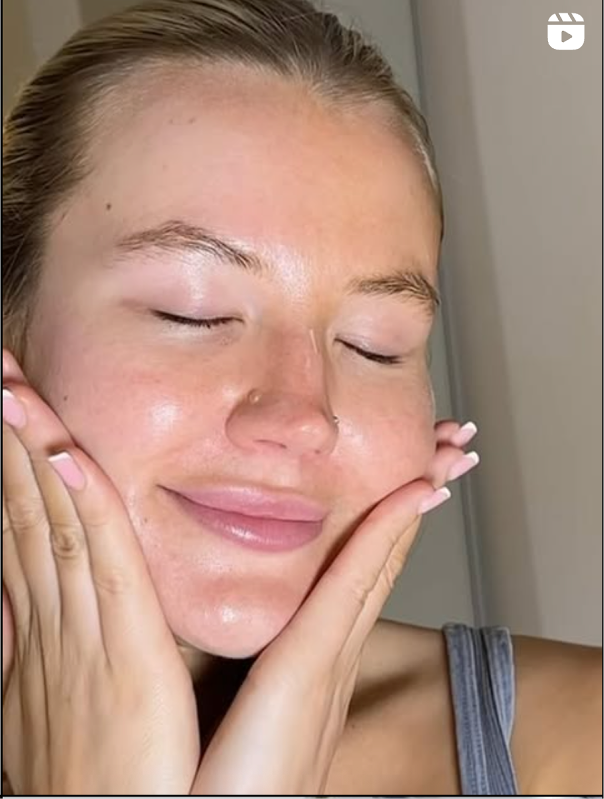 A woman with her eyes closed, gently holding her face with both hands, appears to be enjoying skincare or a facial treatment.