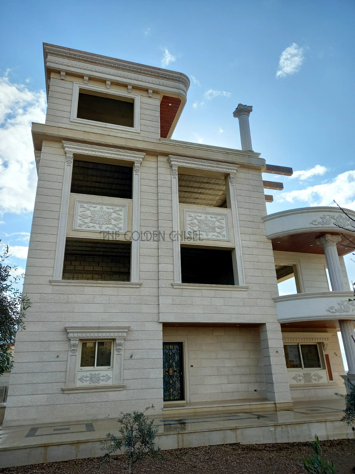 واجهة فيلا فاخرة من الحجر الطبيعي بزخارف وأعمدة كلاسيكية. Luxury stone villa facade with carved details and classical columns.