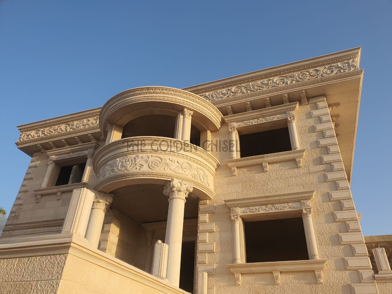 واجهة فيلا فاخرة من الحجر الطبيعي مع شرفات دائرية مزخرفة، أعمدة كلاسيكية ونقوش حجرية يدوية | Luxury natural stone villa facade with ornate curved balconies, classical columns, and hand-carved stone details