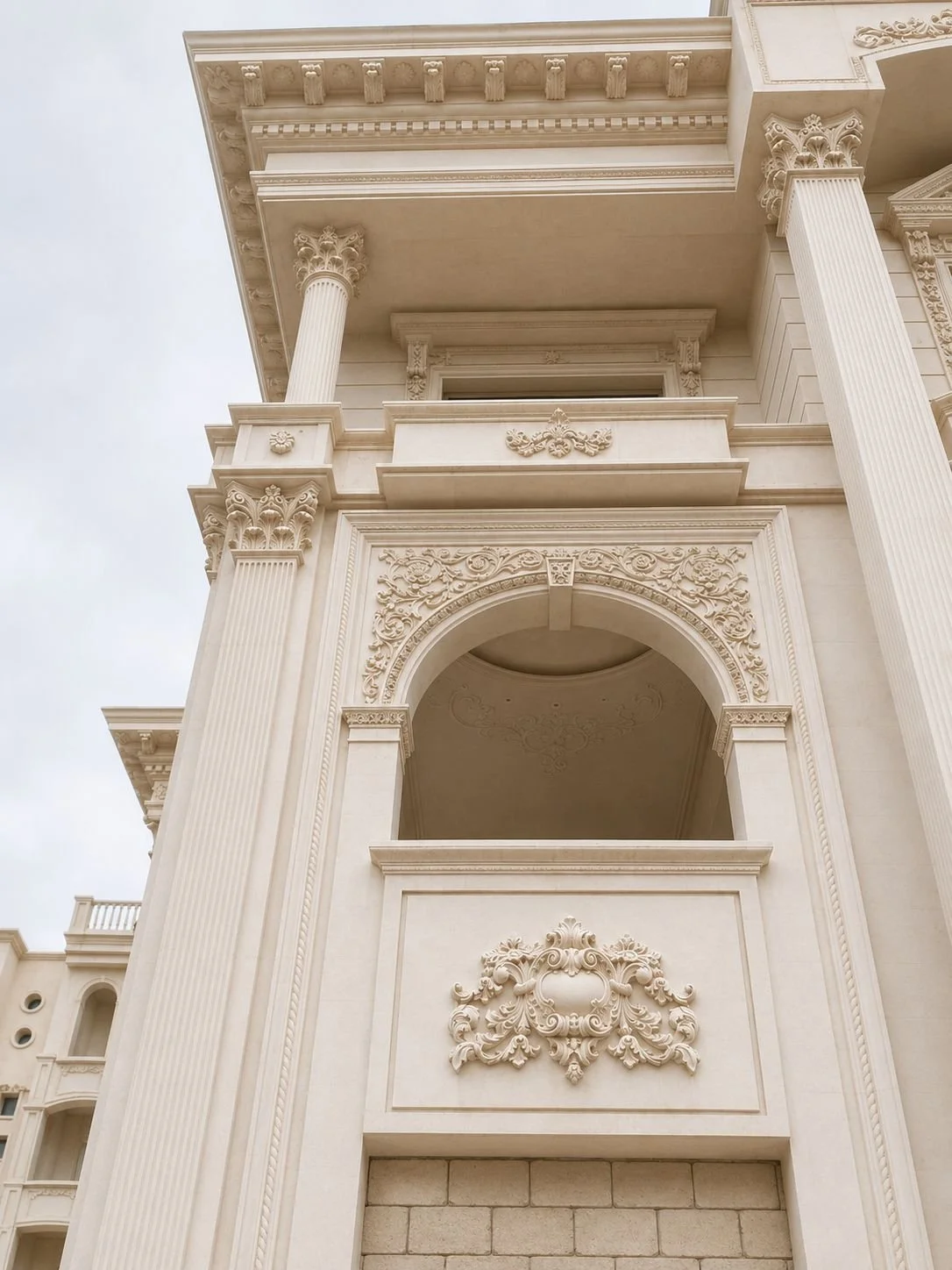 مدخل فيلا فاخر من الحجر الطبيعي مع قوس مزخرف وأعمدة وتفاصيل كلاسيكية. Luxury natural stone villa entrance with an ornate arch, columns and classic details.
