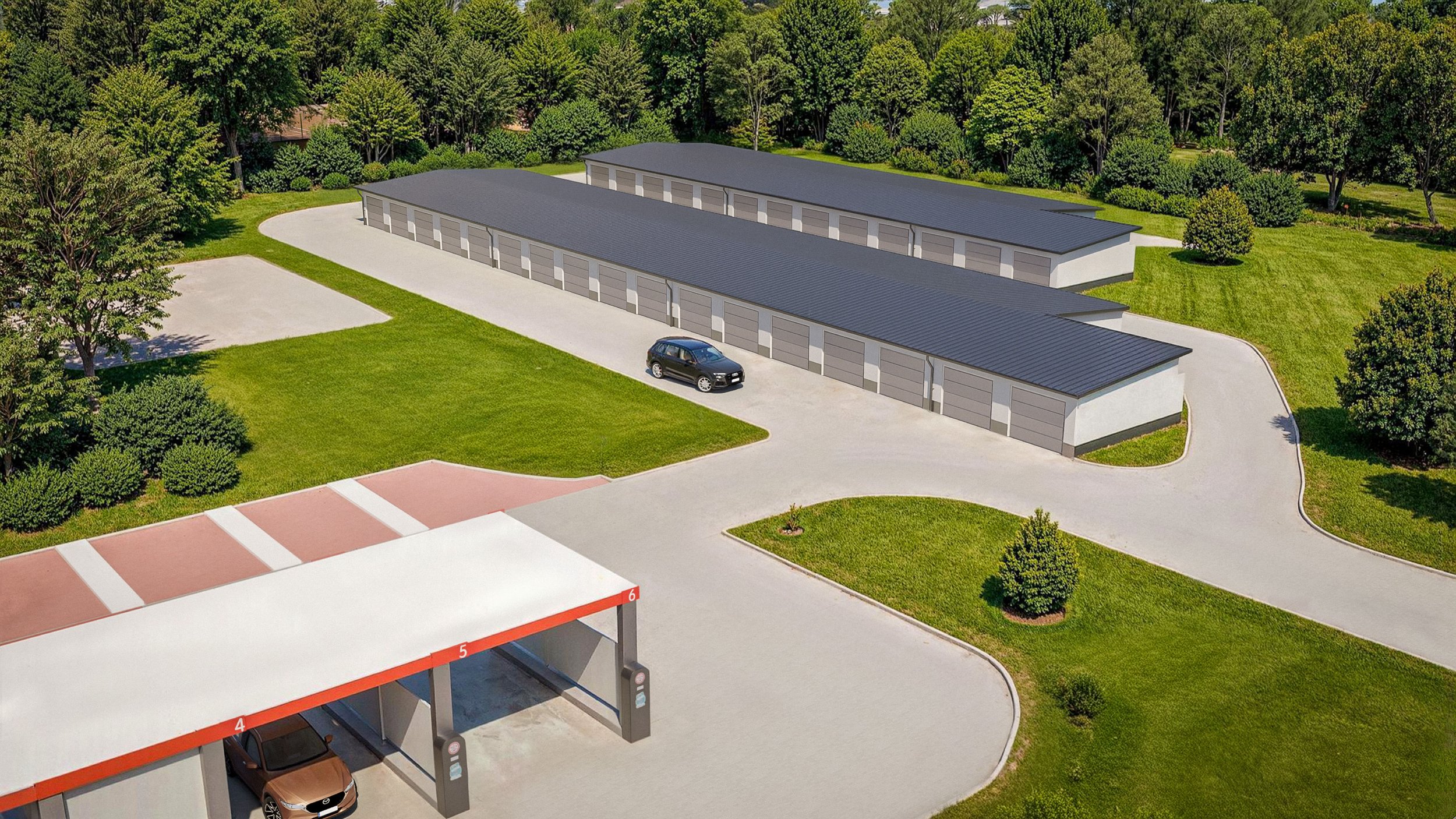 Légi felvétel egy garázs komplexumról: sorolt tárolóegységek, parkoló egy autóval, fedett kocsibeálló két autóval; körben gyep, fák és rendezett kert.