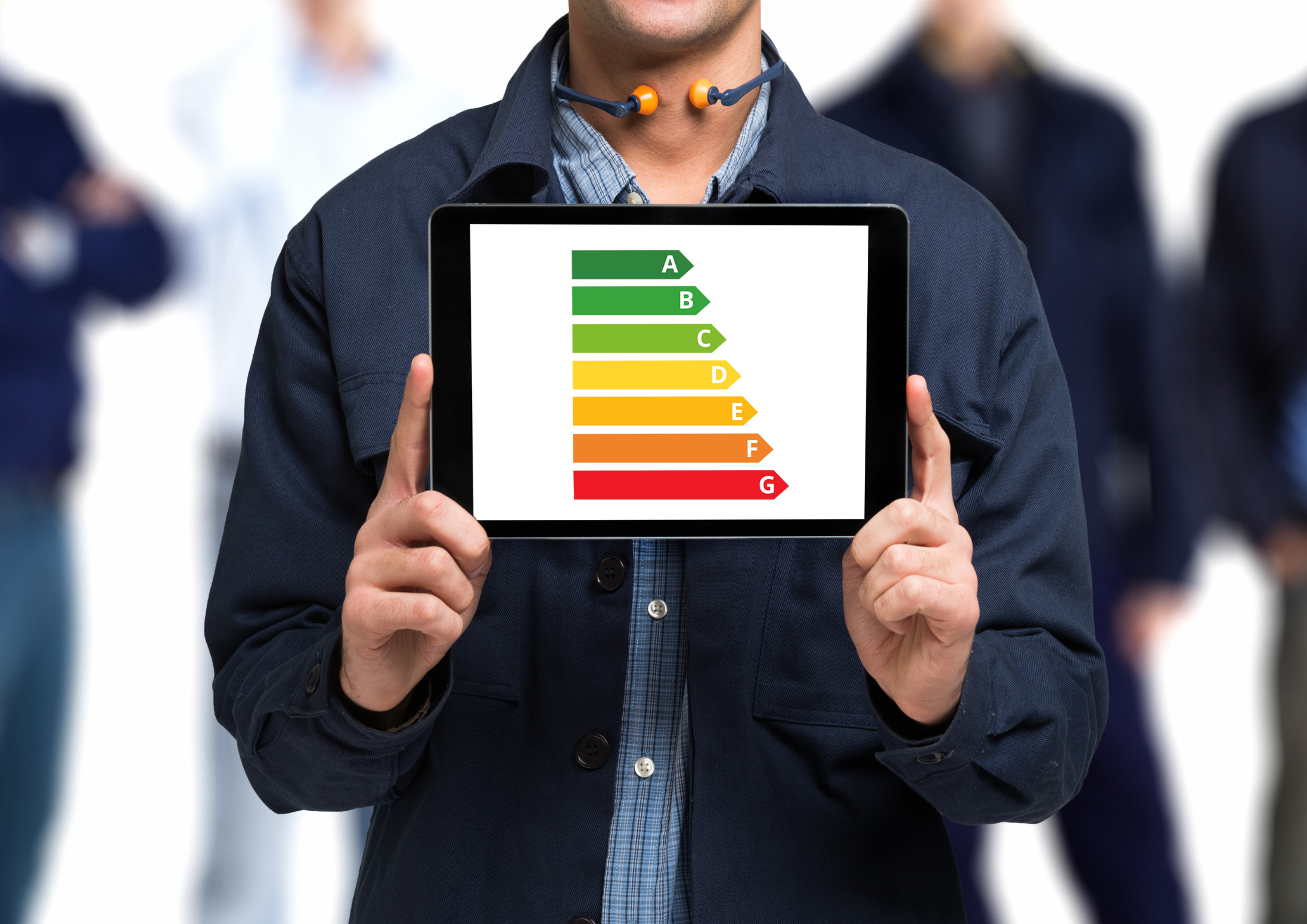 Man holding tablet displaying an energy efficiency rating chart from A to G, with ratings in green to red colors.