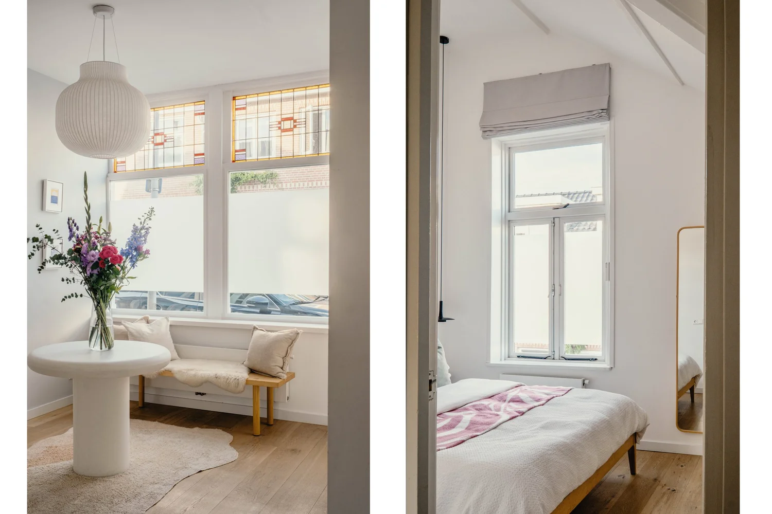 Kamer met grote ramen, een tafel met bloemen en een bed met wit dekbed.