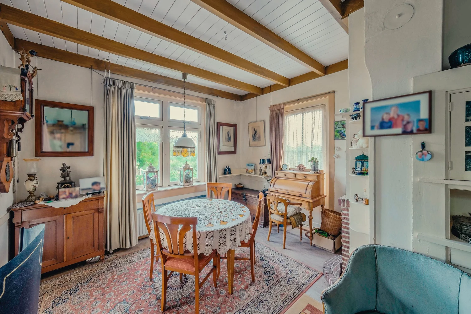 Woonkamer met houten gebogen plafondbalken en een ronde eettafel.