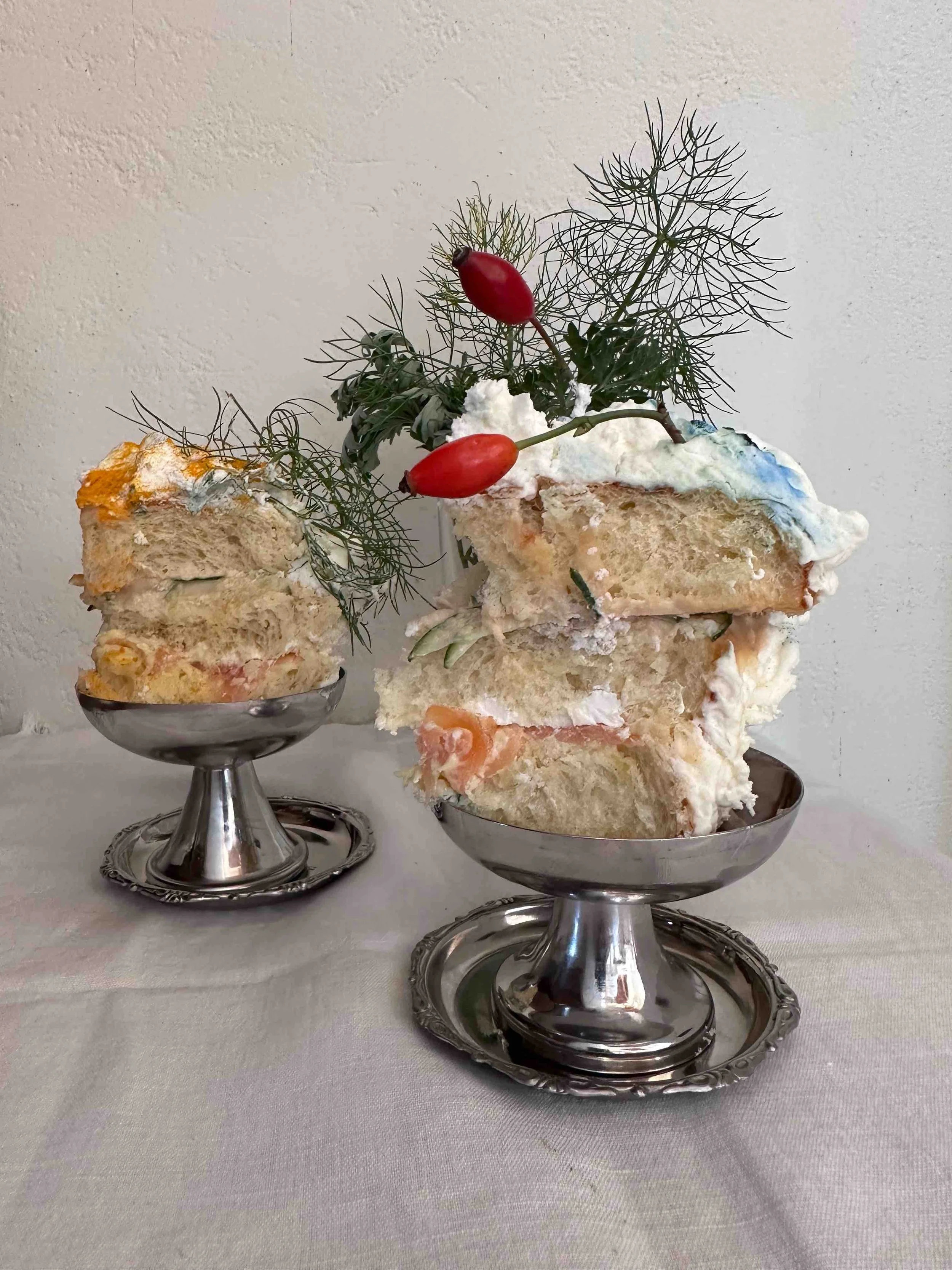 Slices of holiday cake topped with decorative greenery and red berries in silver dessert cups
