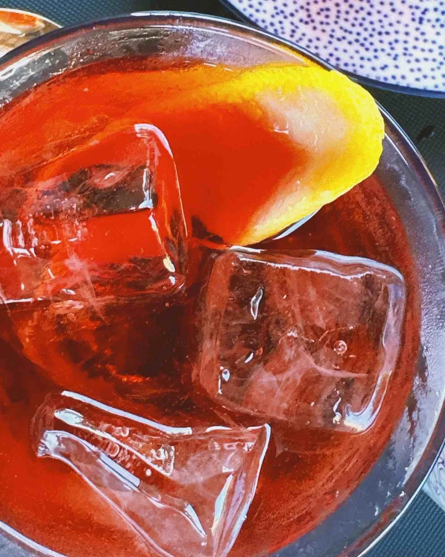 A close-up of a glass of iced Coca-Cola with ice cubes and a lemon wedge.