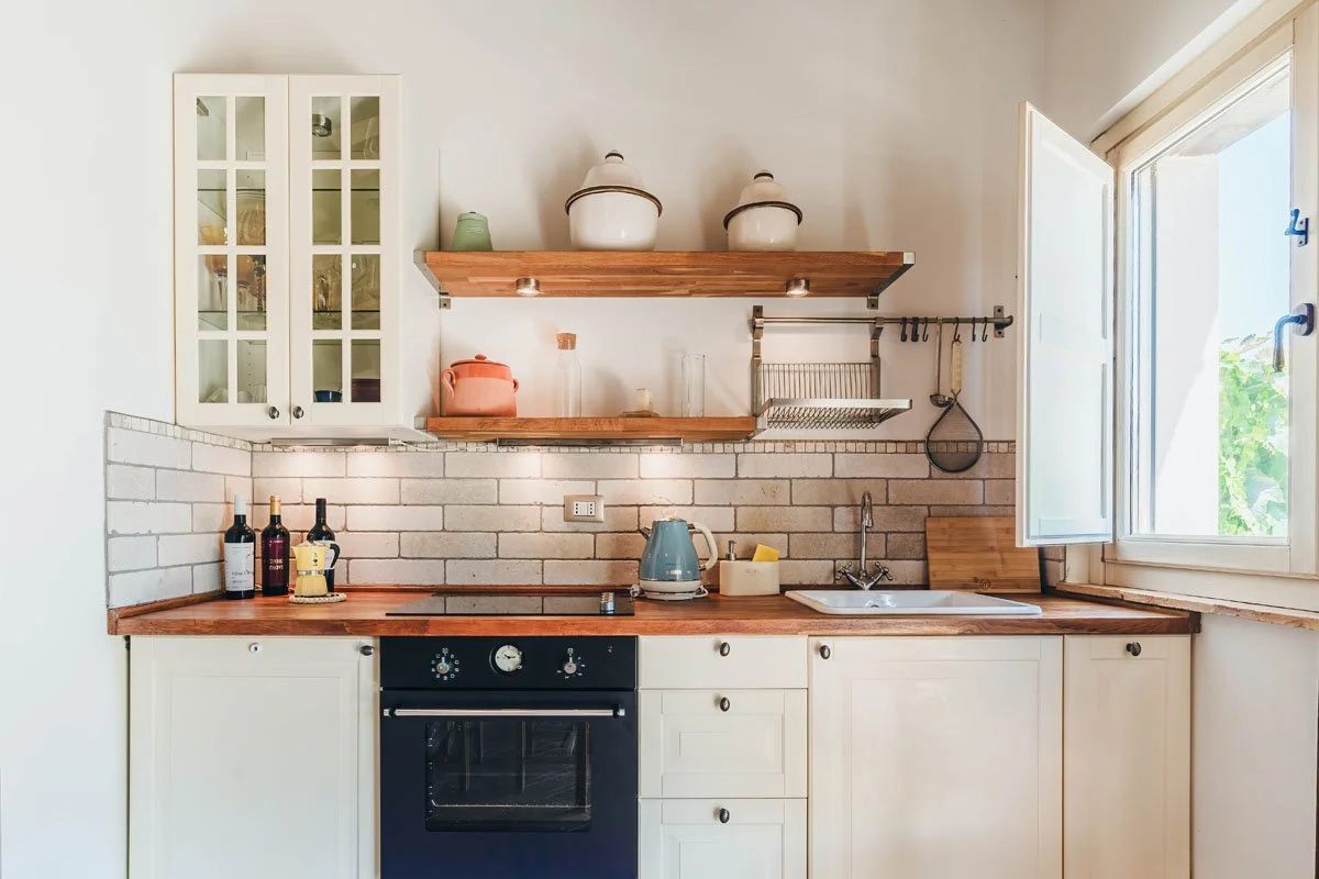 Bright kitchen at Casa Janna with white cabinets, wooden countertop, and an open window