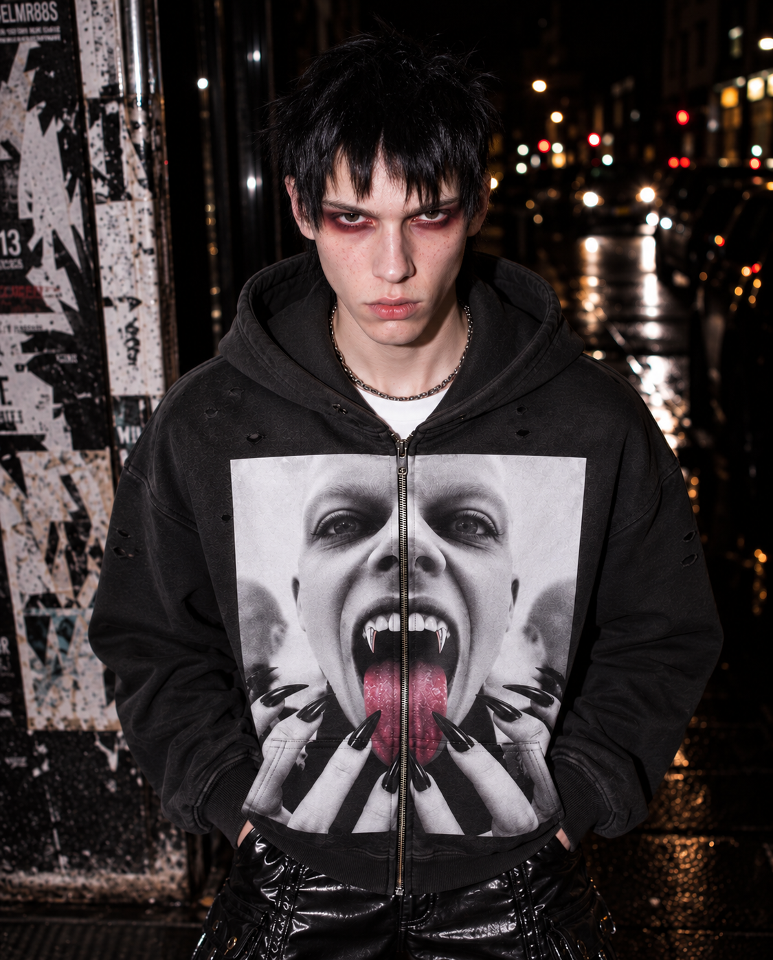 Model wearing a black graphic hoodie with a vampire-inspired design on a wet Berlin street at night.