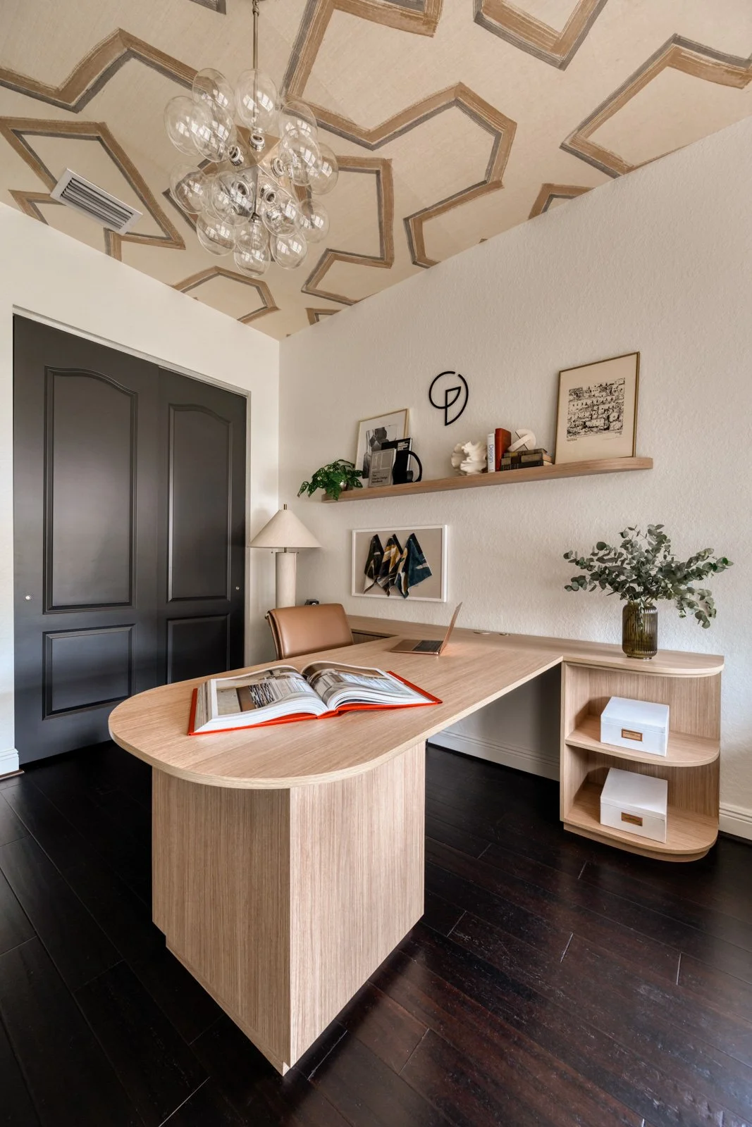 Custom light wood L-shaped desk with rounded edge in a Parkland FL home office designed by Boca Raton interior designer, featuring a geometric patterned ceiling and bubble chandelier