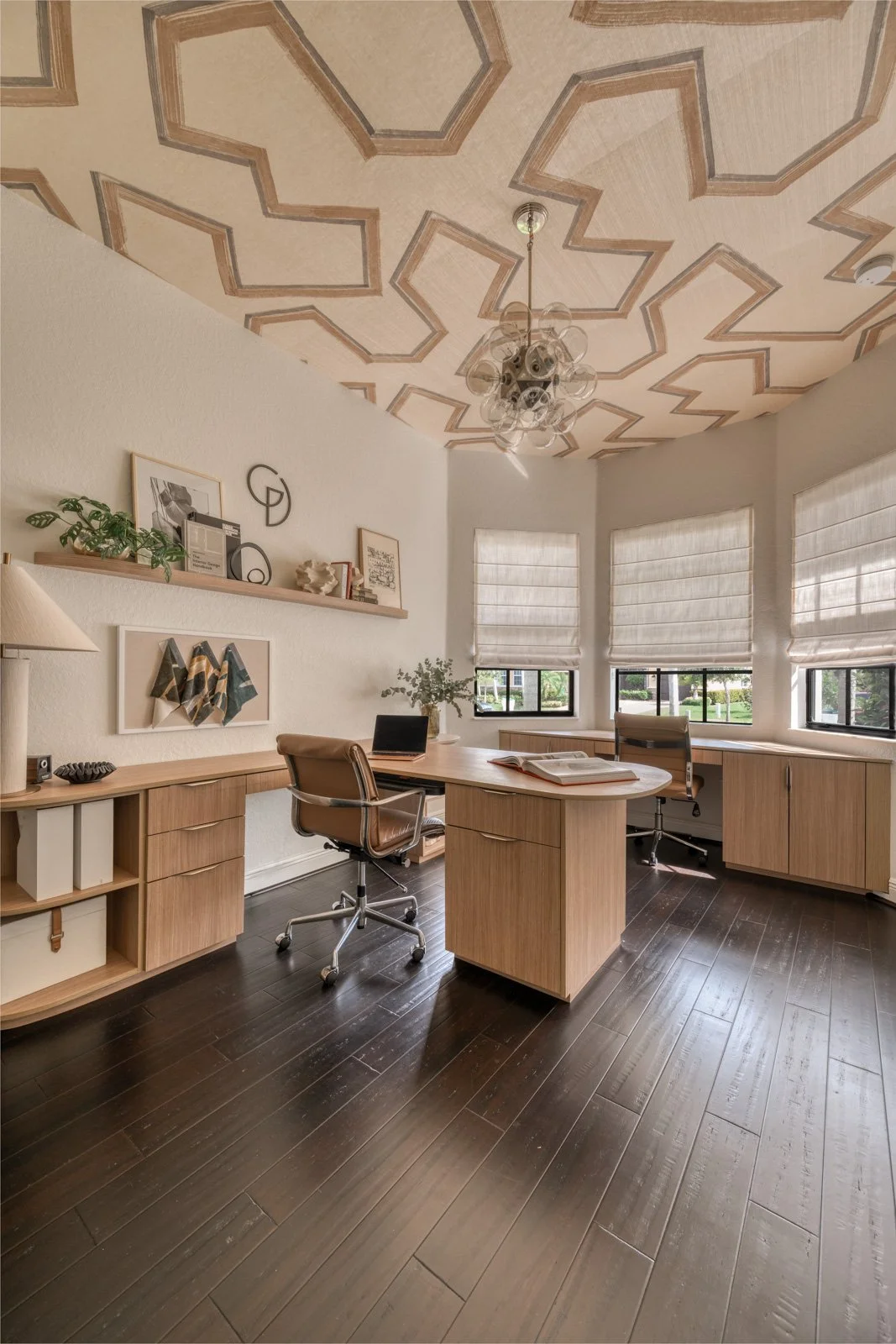 Full view of a Parkland FL home office with custom light wood built-in cabinetry, dual leather task chairs, roman shades, and a hand-painted geometric ceiling by a Boca Raton interior designer