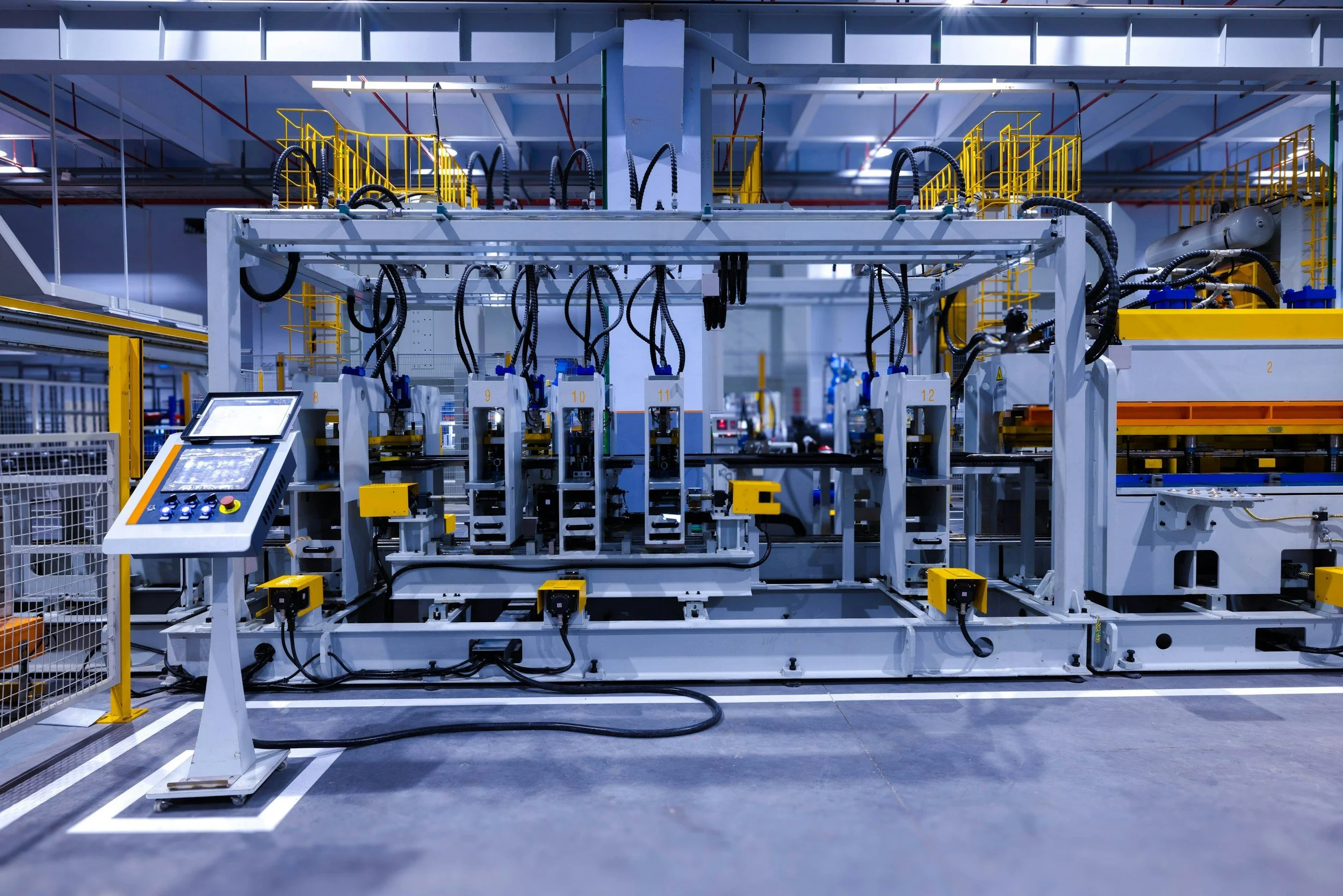 Industrial manufacturing equipment with robotic arms and control panel in a factory setting.