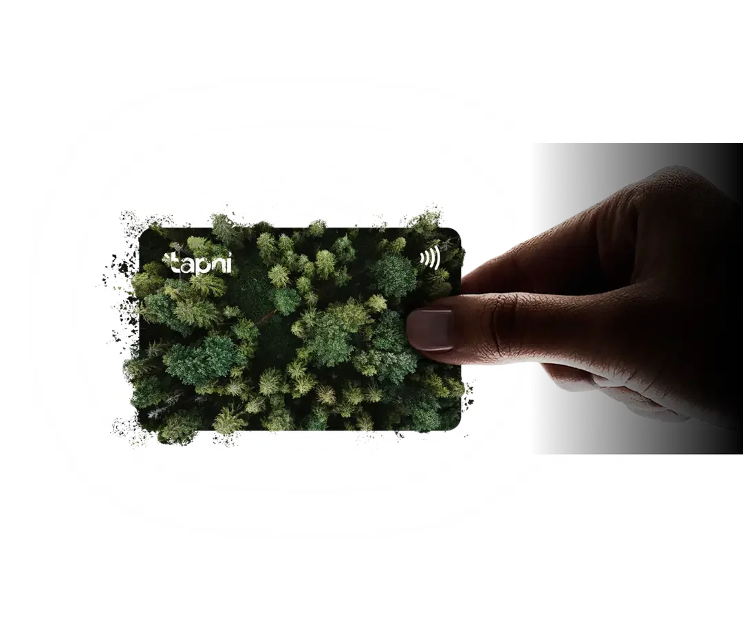 A hand holding a reusable card with a forest of trees on it, near a contactless payment symbol and the word 'tapi' on the card.