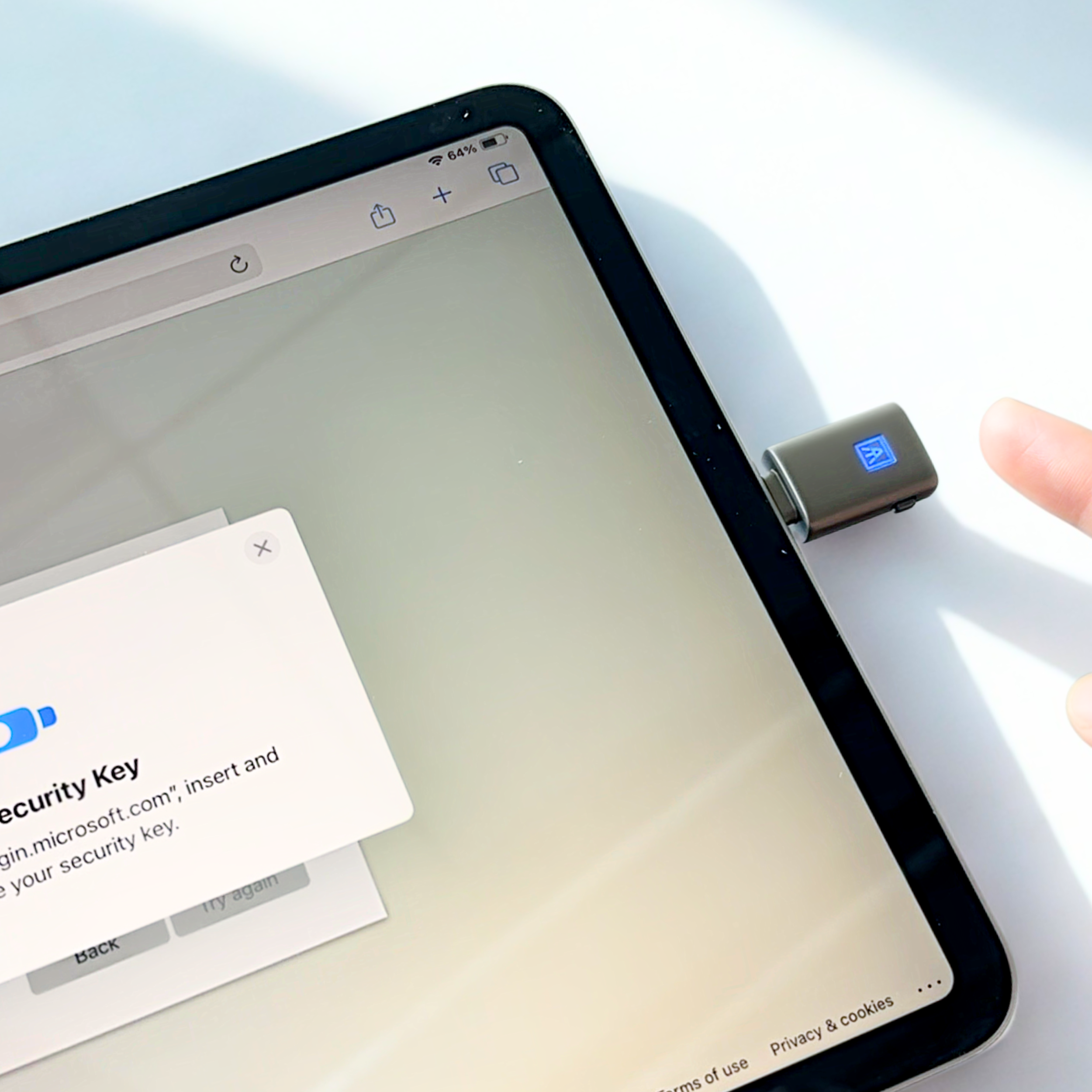 Close-up of a tablet with a pop-up for setting up a Microsoft security key, connected via a USB port on the side, with a finger about to tap the screen.