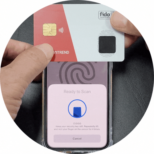 A person holding a red and white FIDO security card above a smartphone with a fingerprint scan screen. The phone displays instructions to keep the security key still on the sensor for four times.