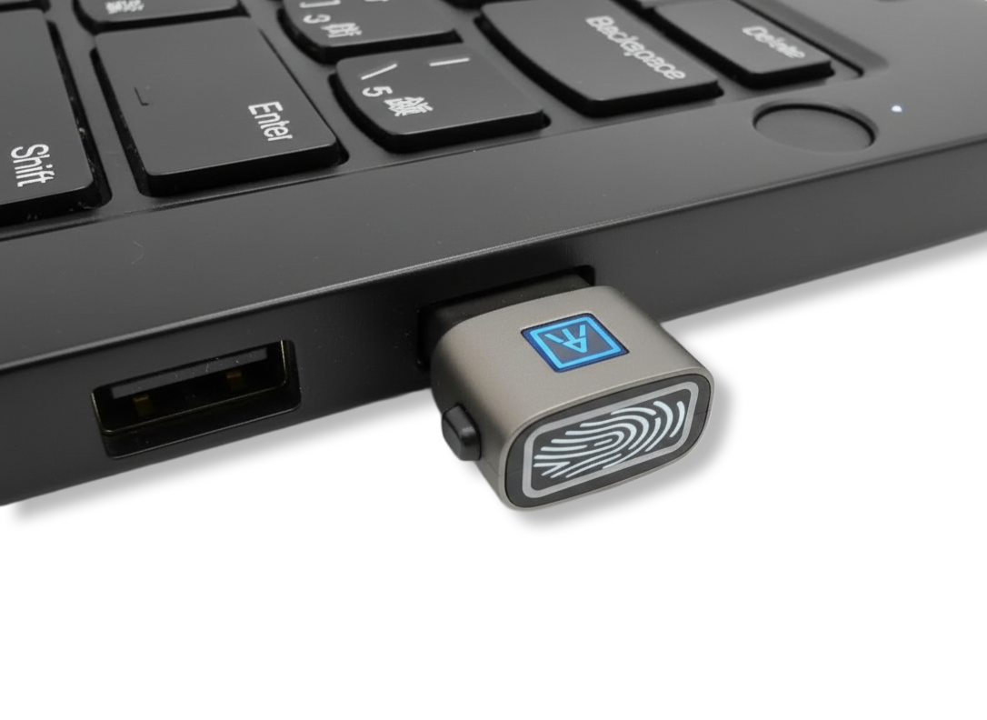 Laptop keyboard with a USB fingerprint scanner plugged into the side.
