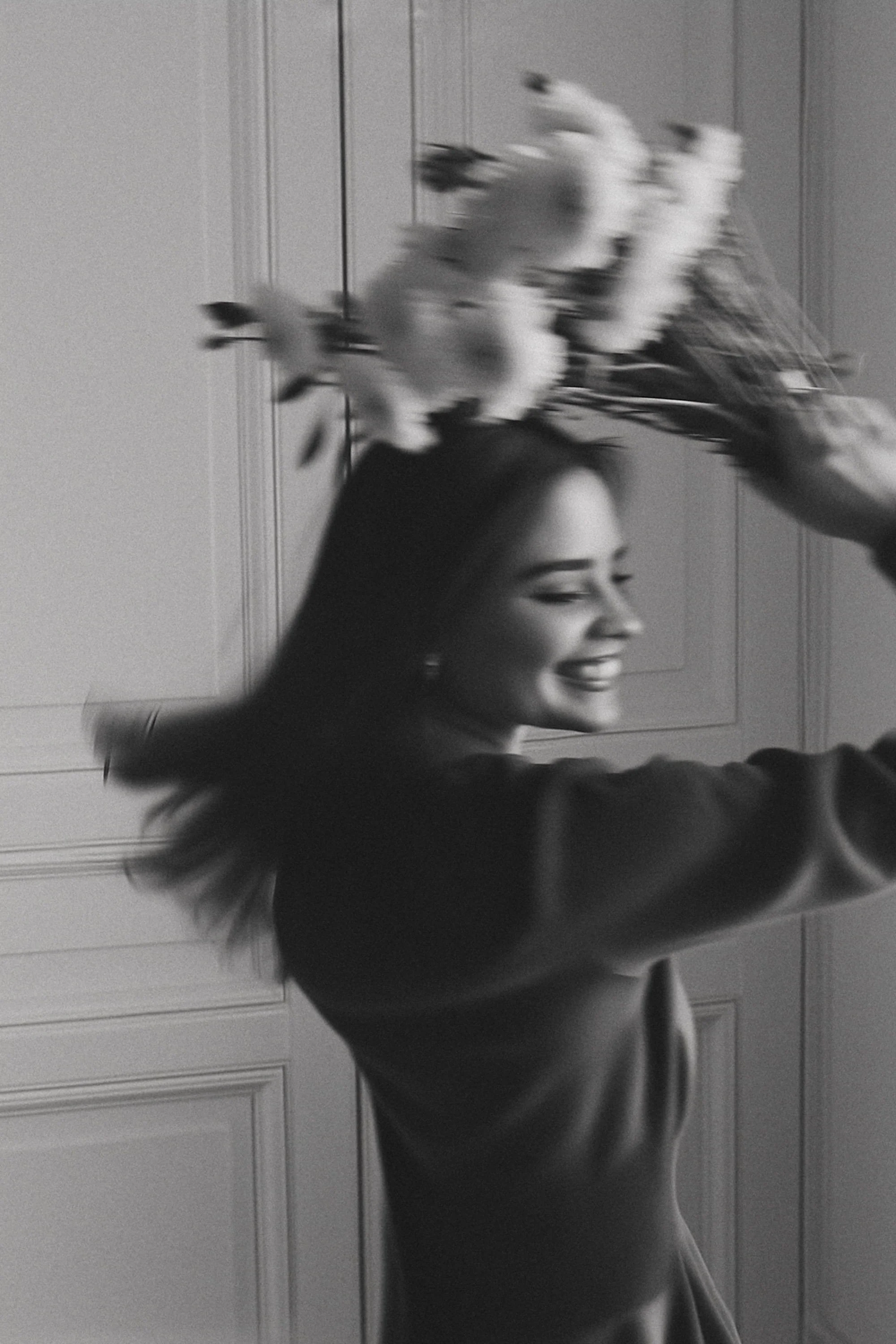 A woman smiling and holding a bouquet of flowers in a room with wooden panel walls.