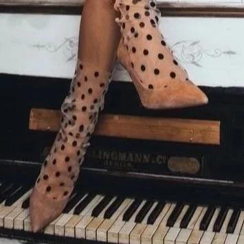 Person sitting on a piano with polka dot boots