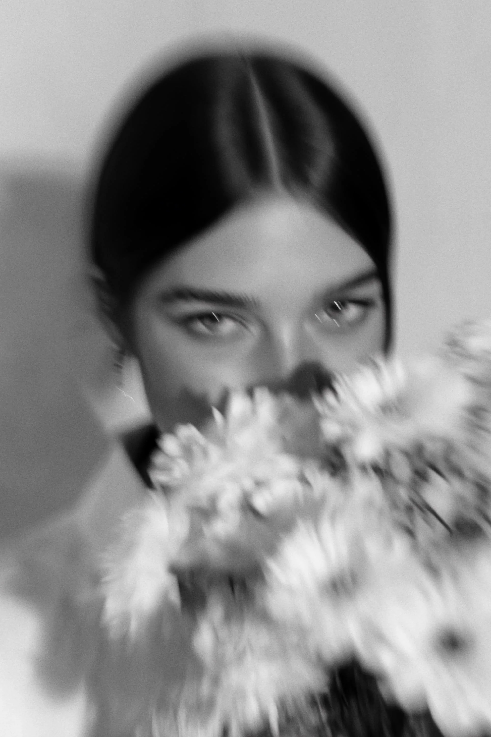 A portrait of a young woman with dark hair holding a bouquet of flowers.