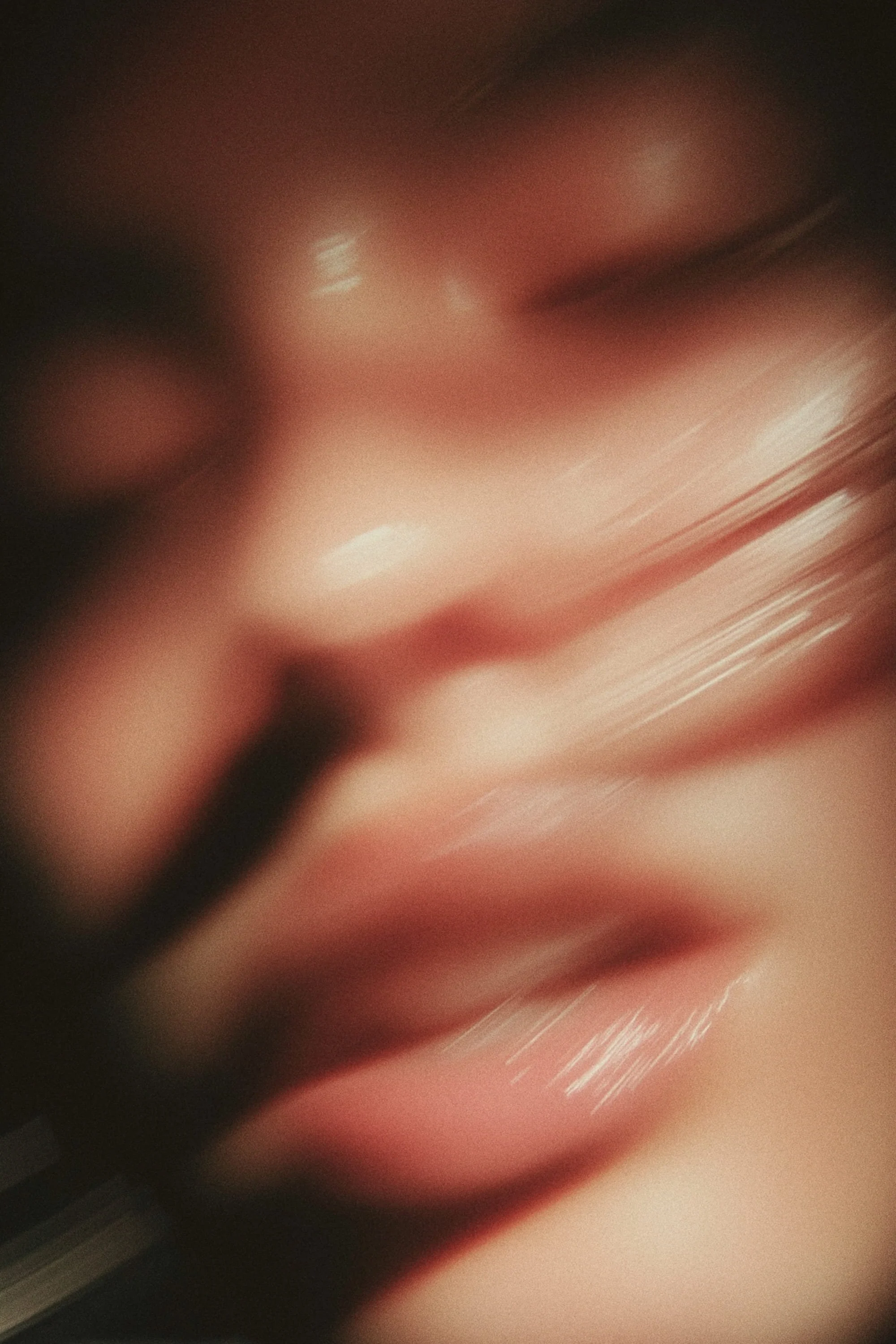 A blurred close-up of a person's face, focusing on their lips and part of their hand near the mouth.