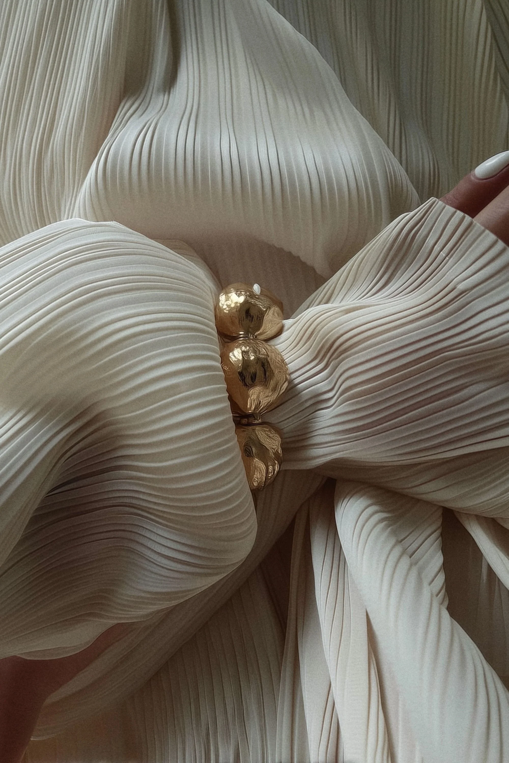Close-up of a beige pleated fabric with three gold foil balls resting on it.