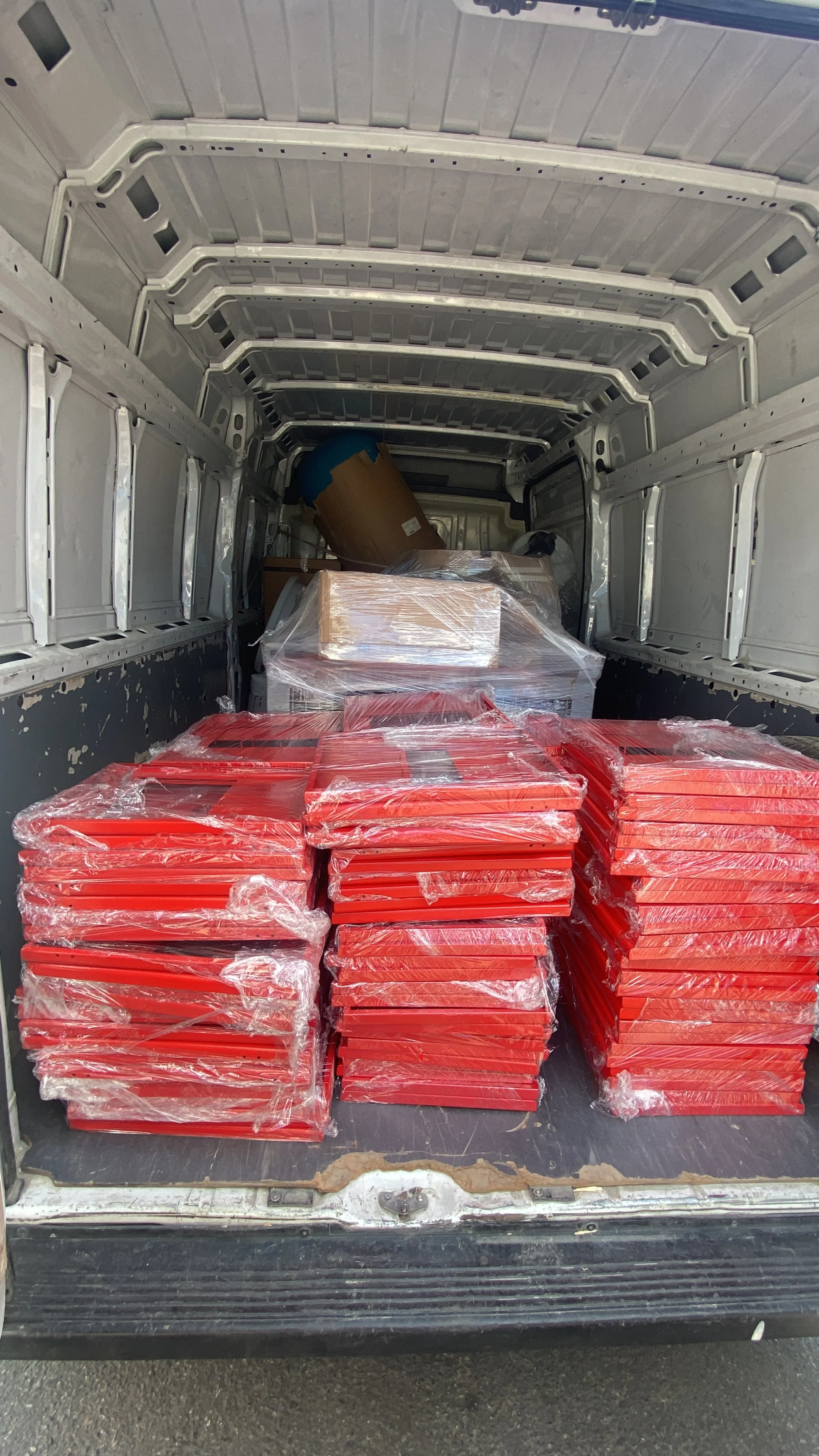 Open back of a delivery van filled with stacks of wrapped frozen pizzas and boxes.