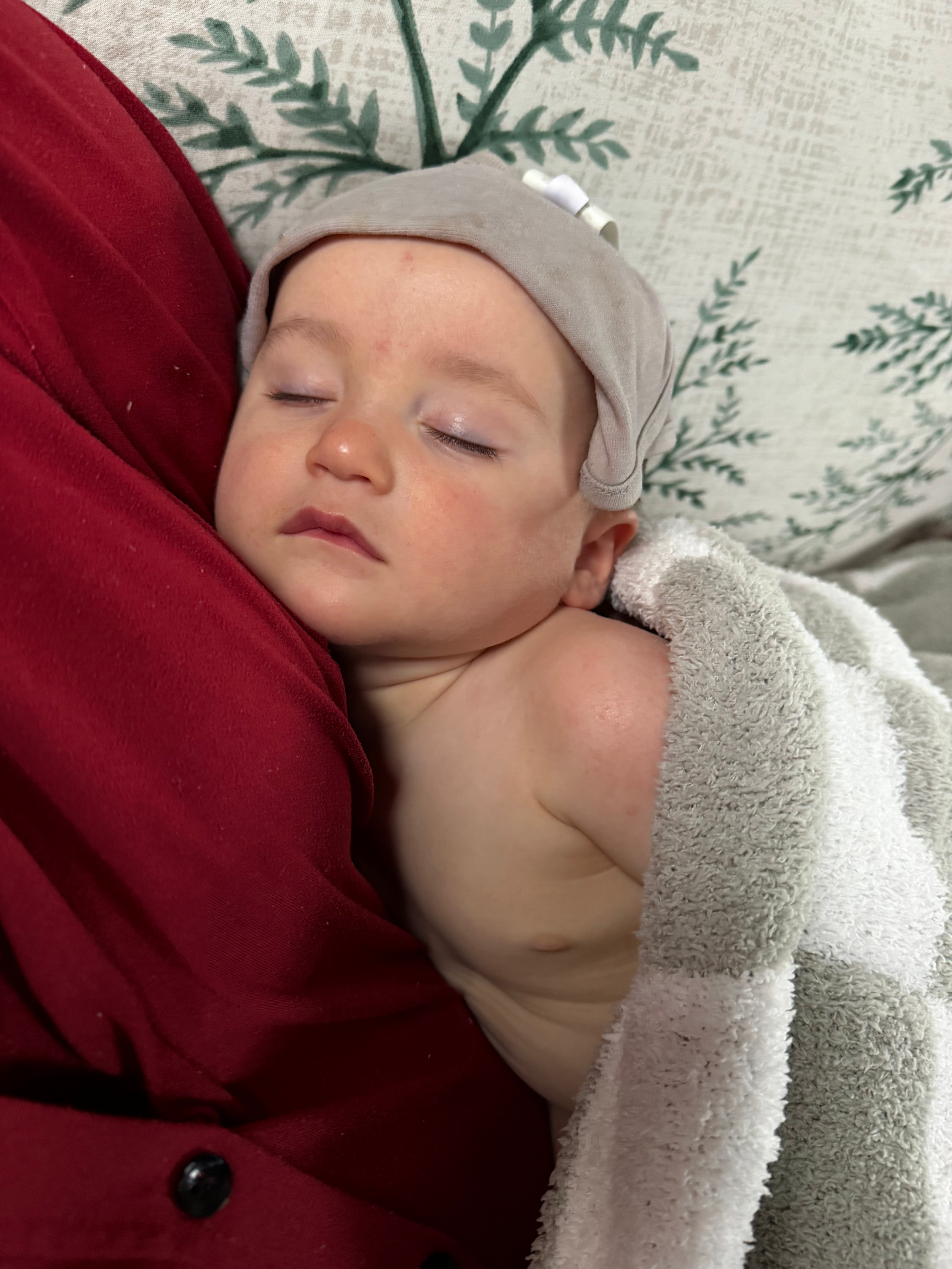 One-year-old sleeping peacefully on his mother's shoulder while recovering from illness.