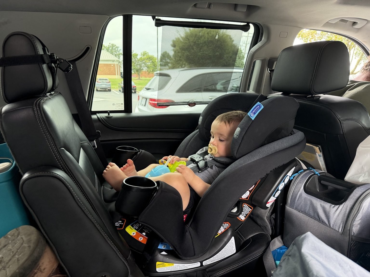Toddler riding rear-facing in his car seat inside a Yukon packed for a family road trip.