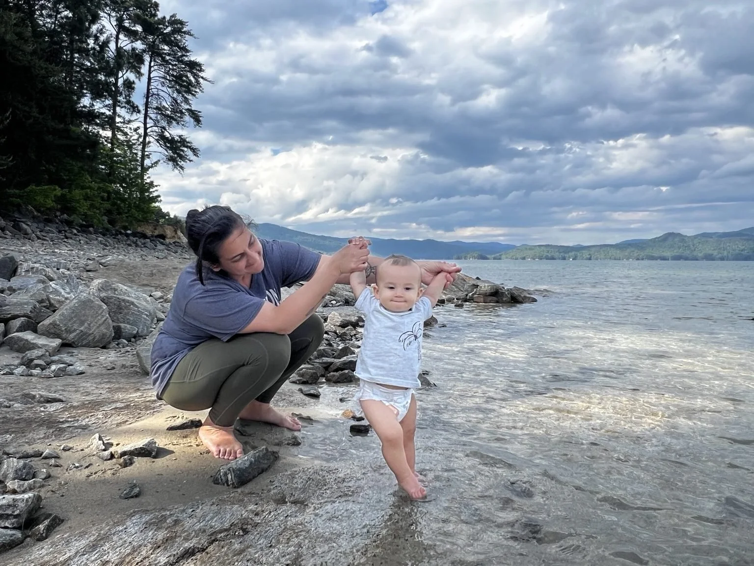 Mom helping her toddler walk into Lake Jocassee at Devils Fork State Park in South Carolina.