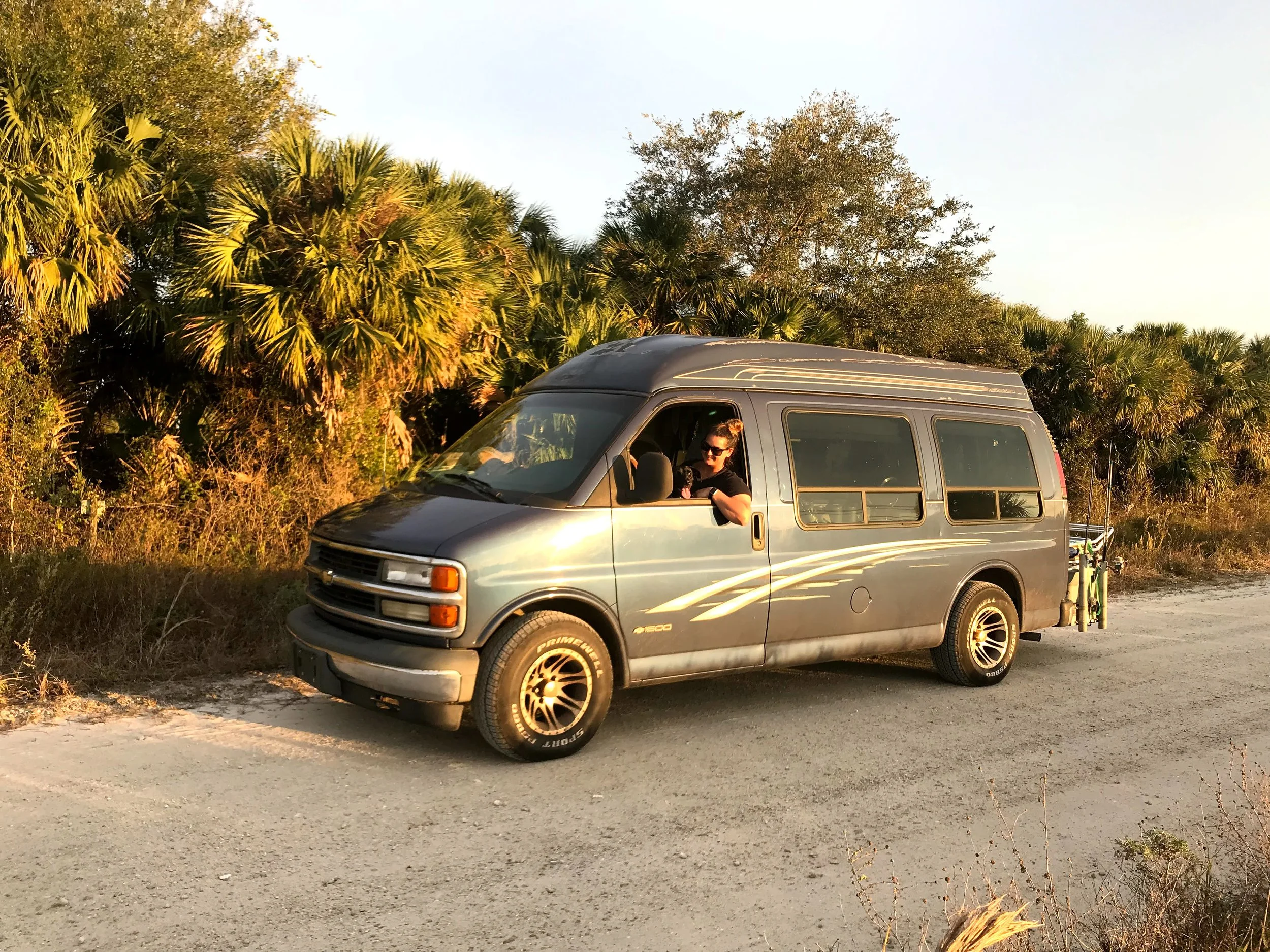 Blue Chevy van parked on a gravel road, loaded up for travel, during early vanlife travels, representing the beginning of life on the road.