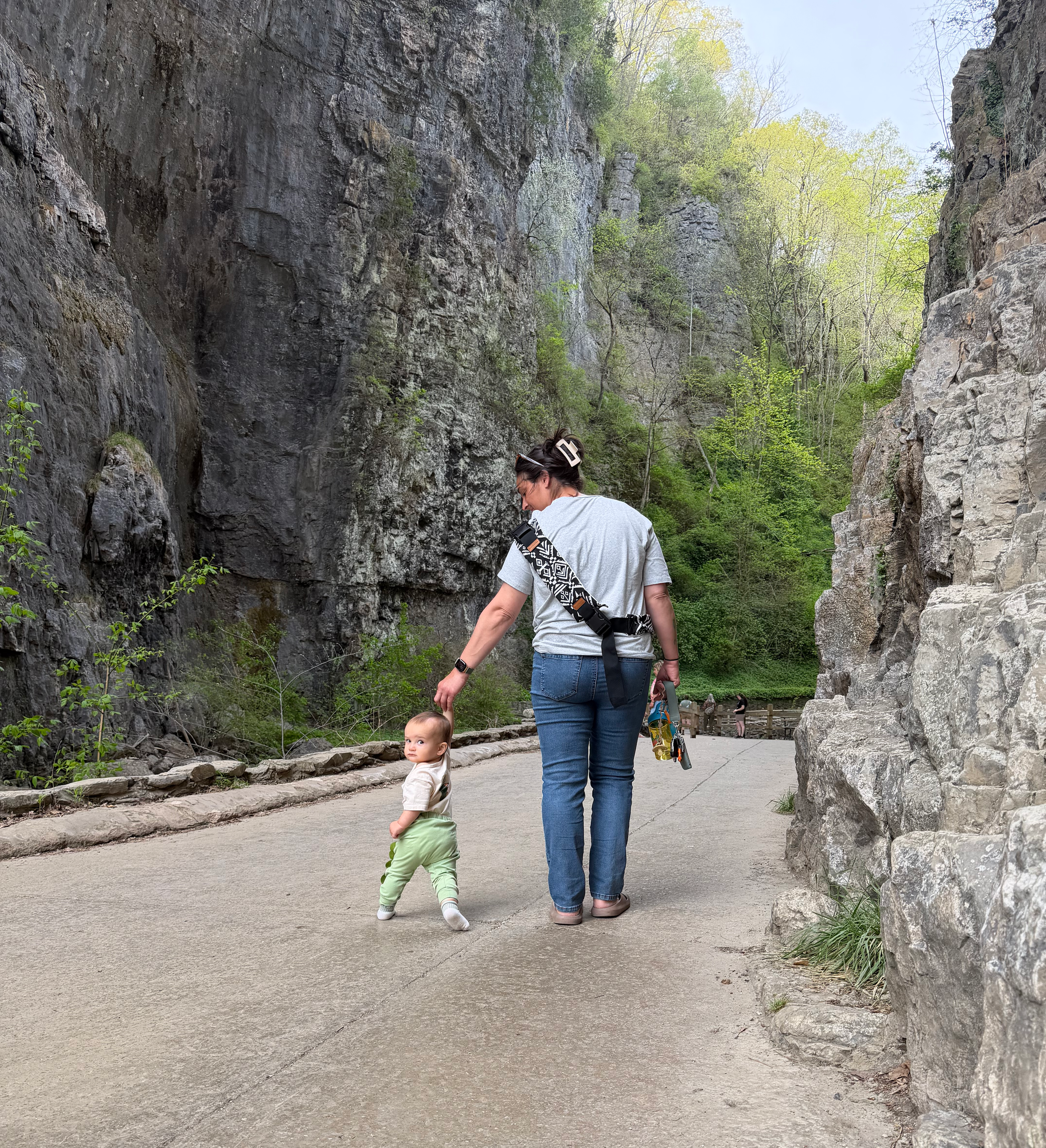 Mother holding her toddler's hand while walking beneath Natural Bridge in Virginia.