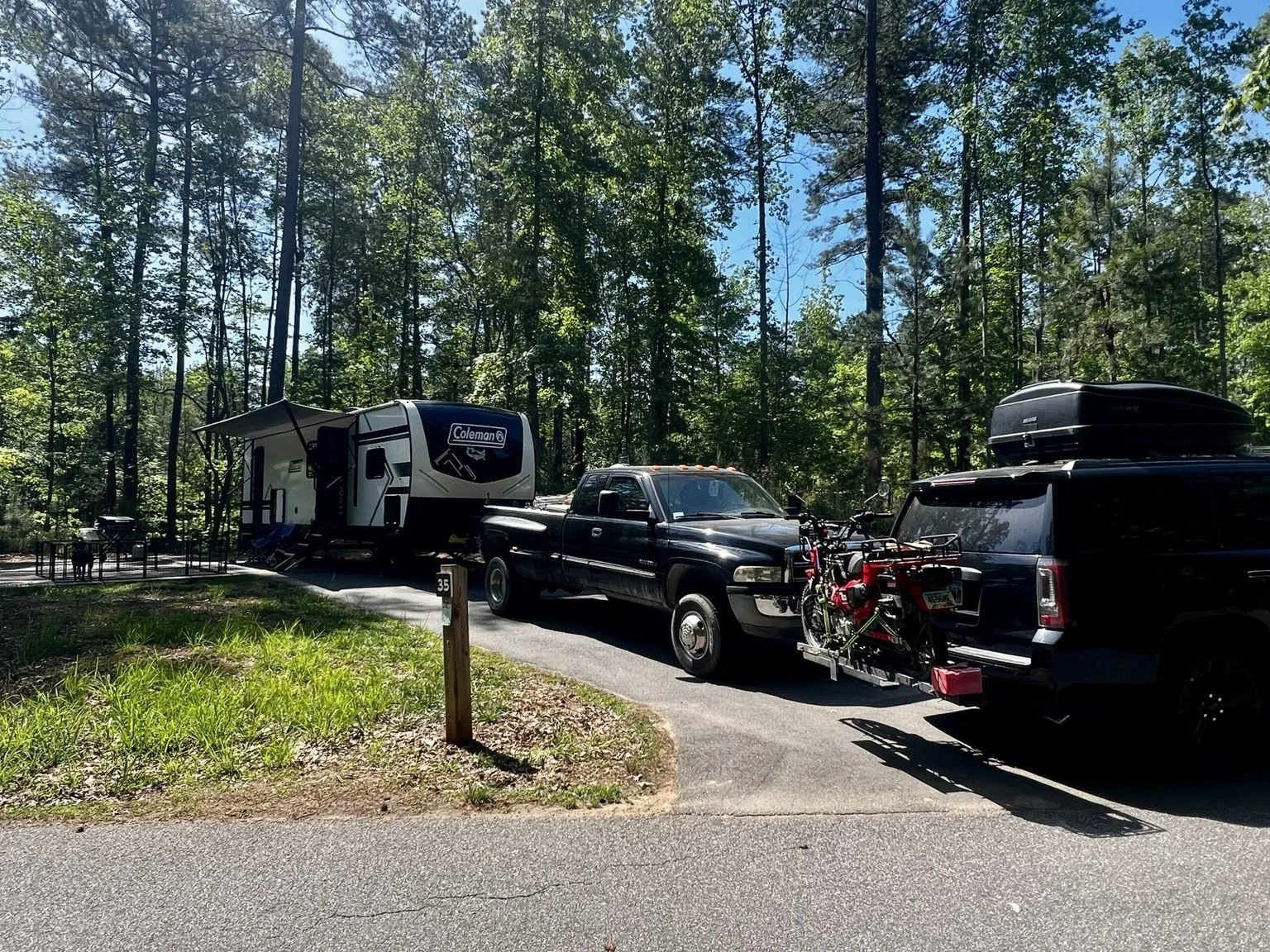 Travel trailer, dually truck and SUV parked together at a wooded campsite at Lake Norman State Park in North Carolina.