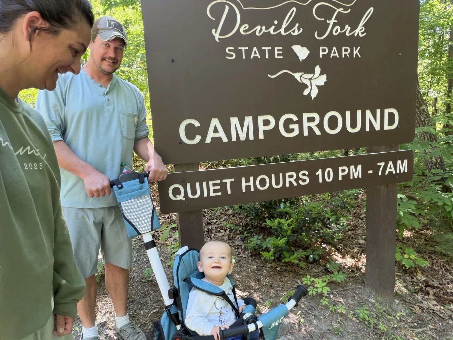 Family standing with Banks in his tricycle beside the Devils Fork State Park campground sign in South Carolina.