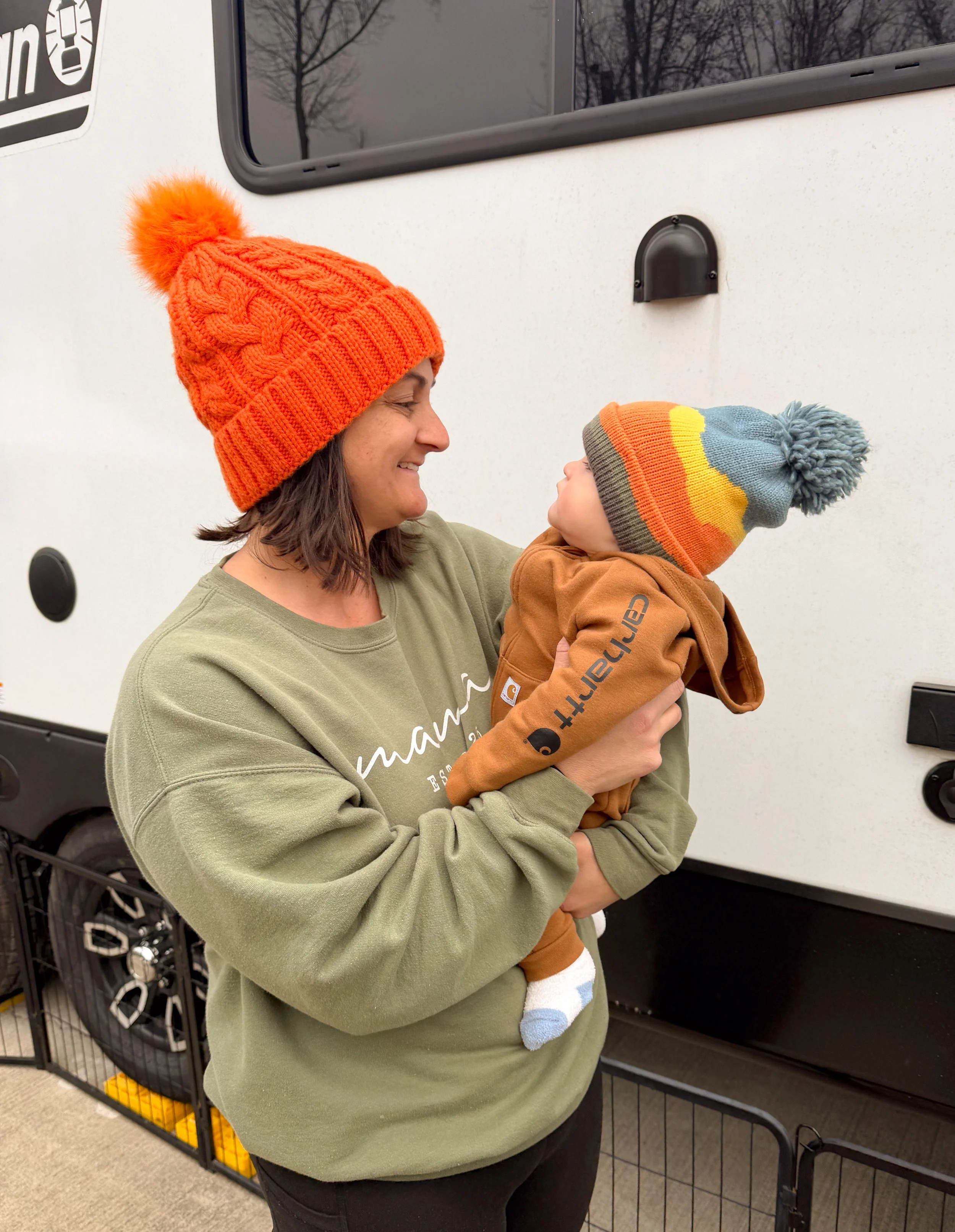 Mother holding her baby outside an RV during everyday life living full-time on the road with a baby.