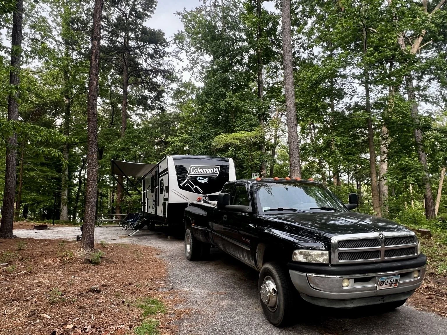 Black pickup truck and travel trailer at a wooded campsite at Devils Fork State Park before leaving South Carolina.