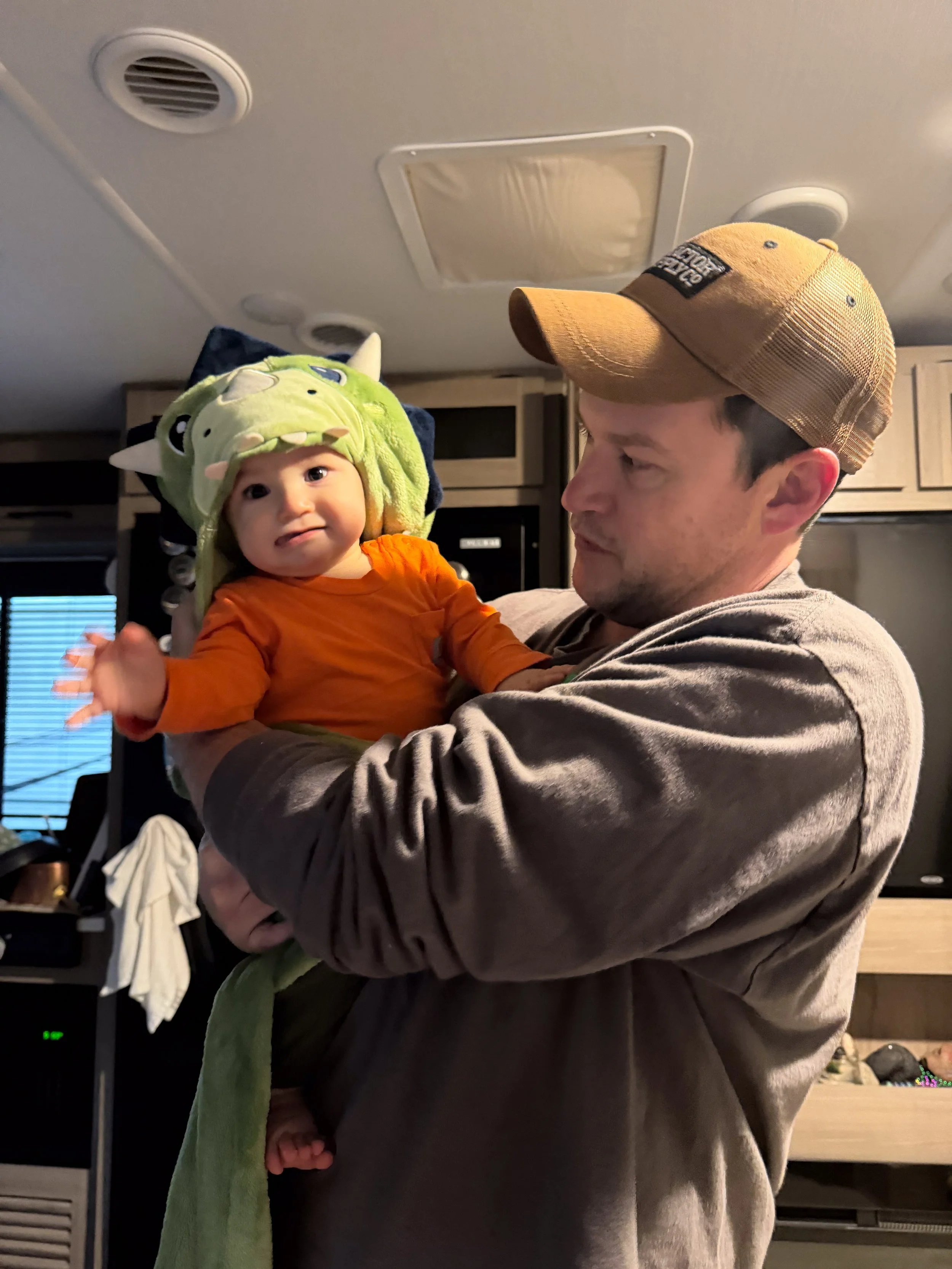 Father holding his baby inside an RV during everyday family life, capturing parenthood and routine while living full-time on the road.