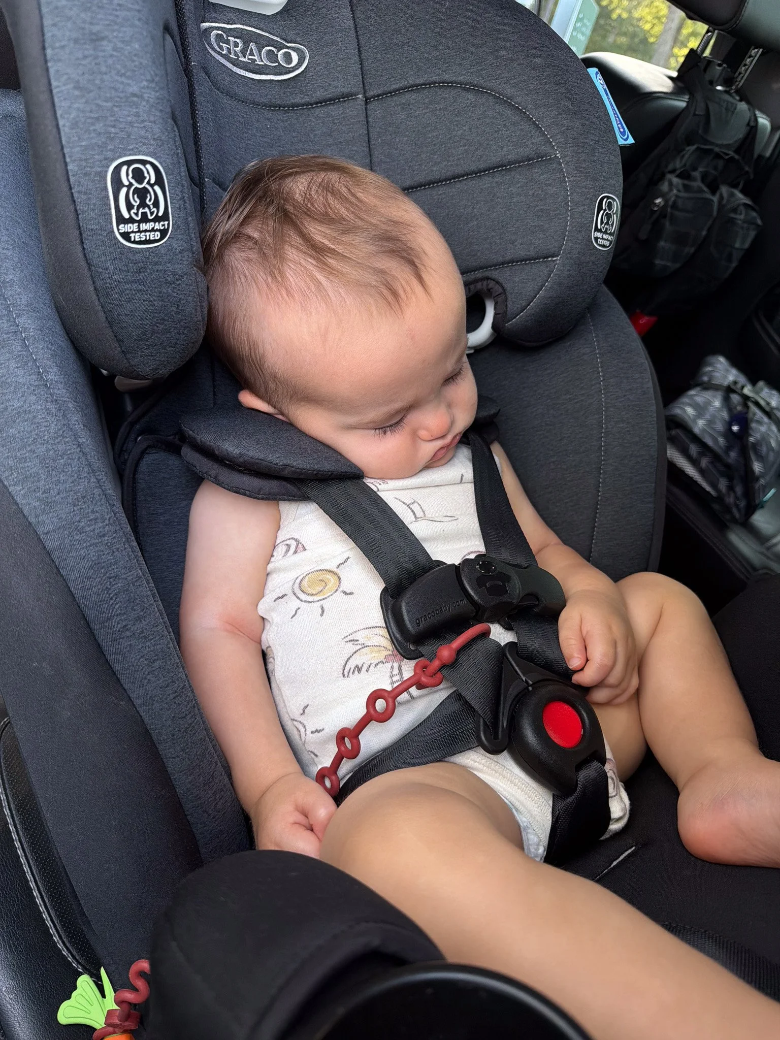 One-year-old Banks asleep in his car seat during a family travel day.