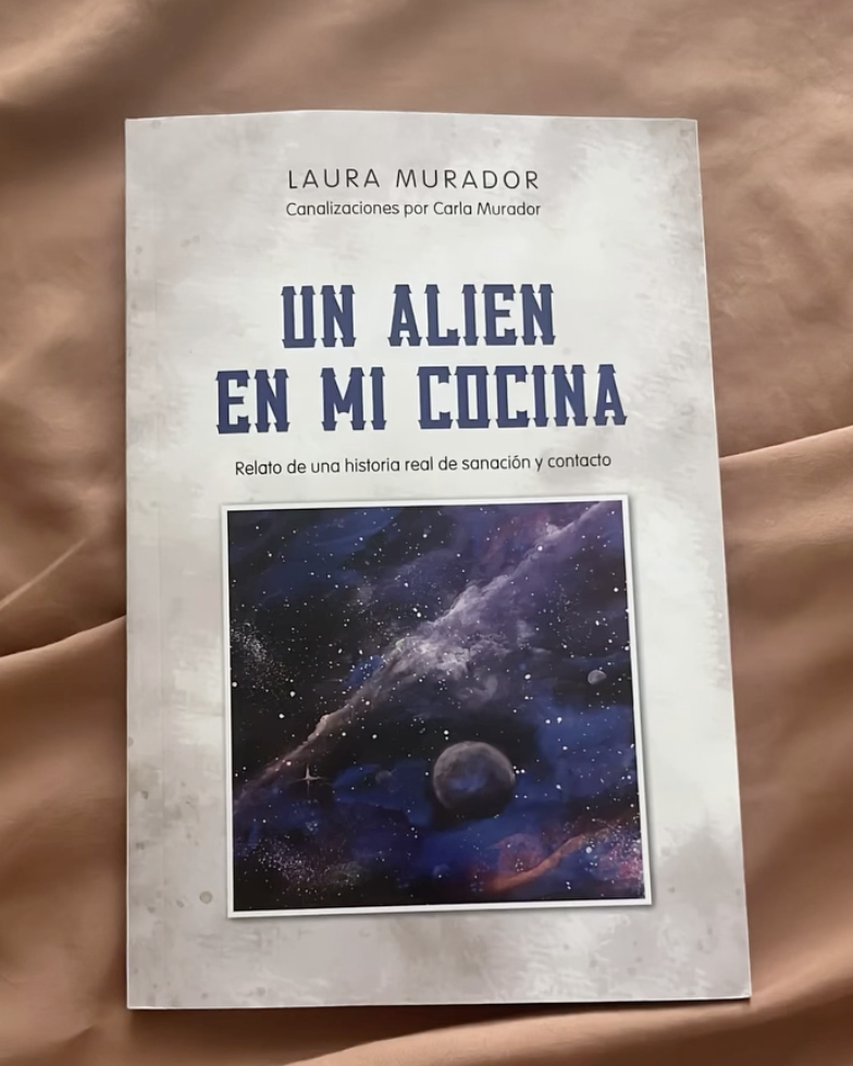 Cover of a book titled 'Un Alien en Mi Cocina' by Laura Murador, featuring a cosmic galaxy scene with planets and stars.
