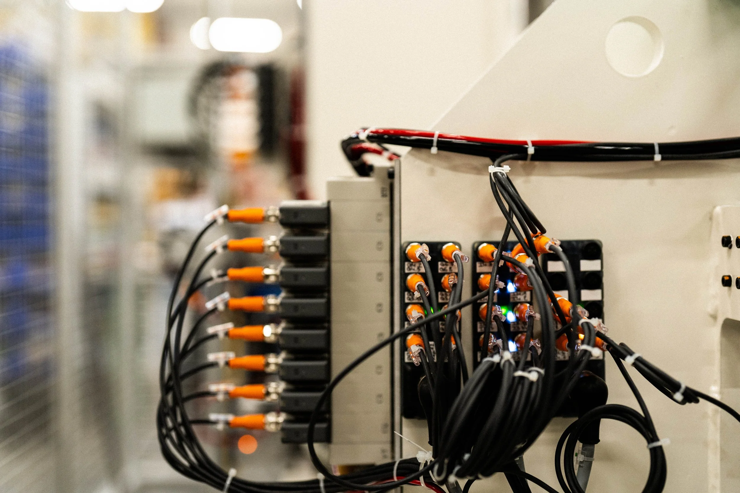 Un panneau électrique avec de nombreux fils, connecteurs et voyants lumineux dans un environnement technique.